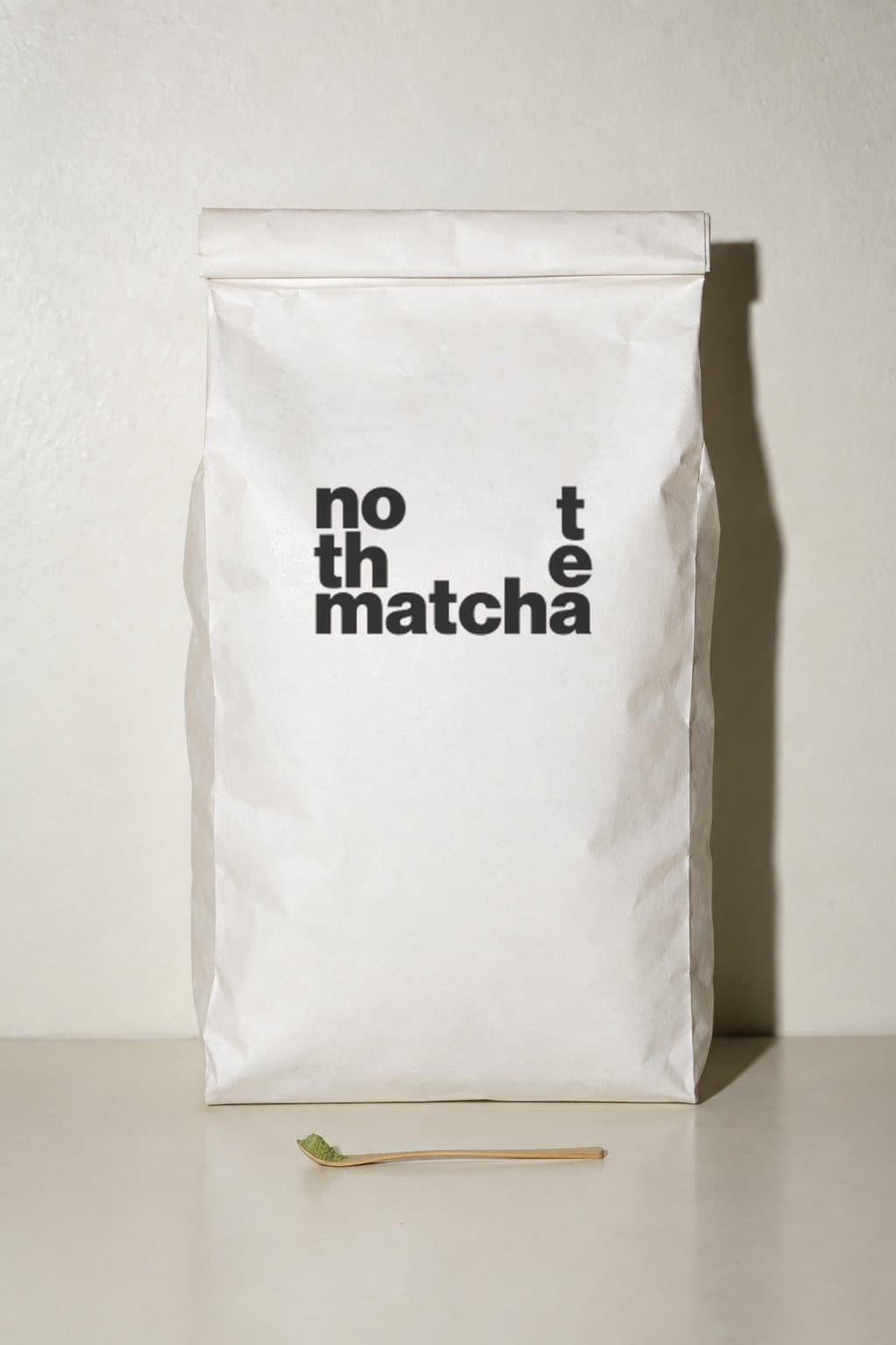 A large bag of NOT THE MATCHA next to a tiny bamboo tea scoop