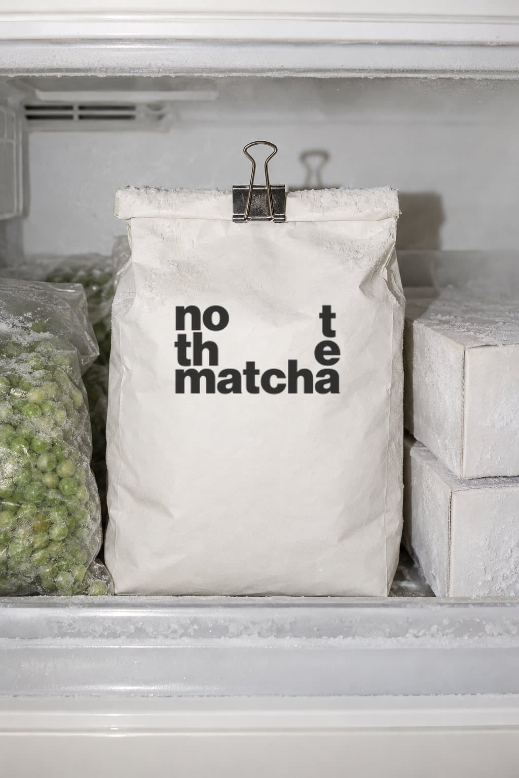 A bag of NOT THE MATCHA clipped shut in a freezer drawer next to frozen peas
